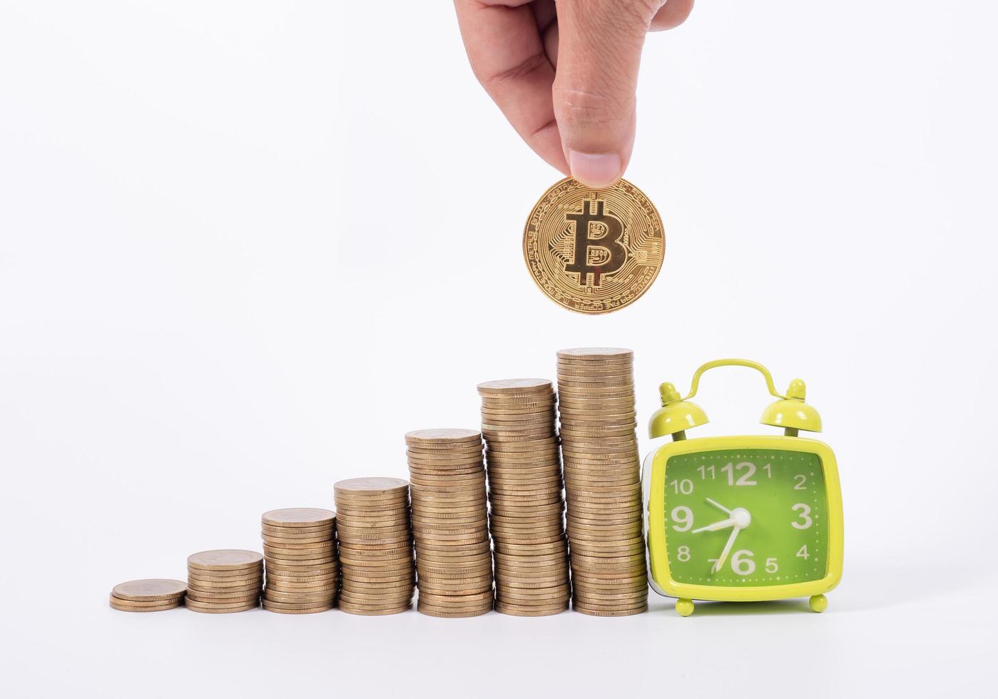 mano sosteniendo bitcoin y muchas monedas y reloj para ahorrar dinero concepto sobre fondo blanco foto
