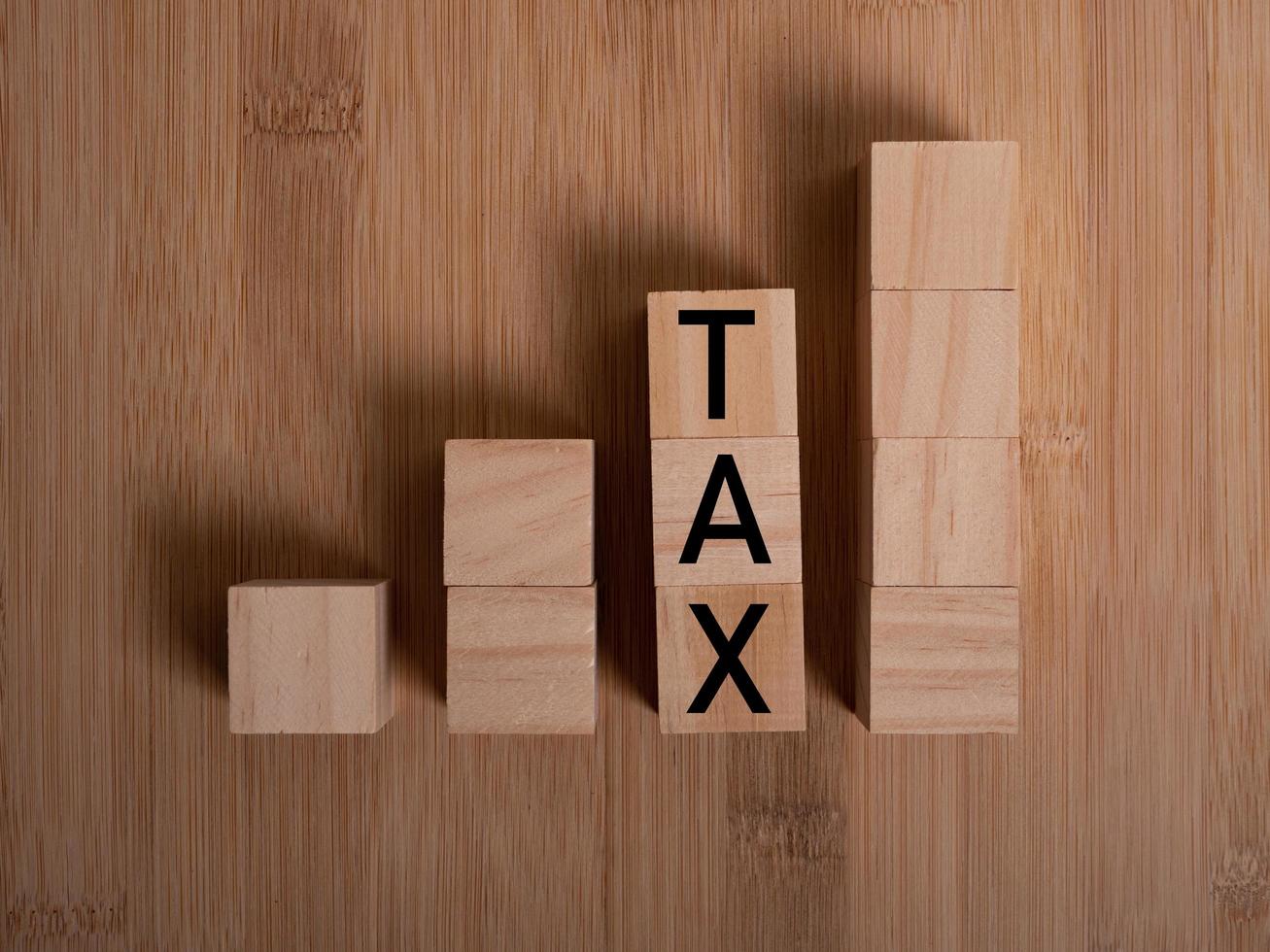 Tax with wooden alphabet blocks, on plank wooden background with copy space photo