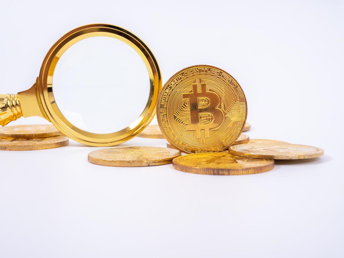 Golden Bitcoin replica and magnifying glass on white   background.Business and finance concept. photo
