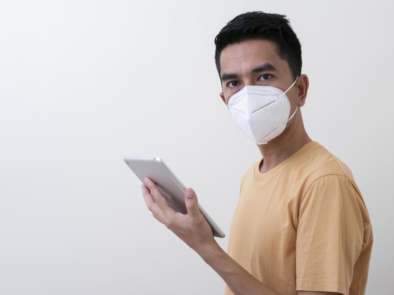 hombre con tableta digital usa mascarilla quirúrgica para protegerse del virus foto