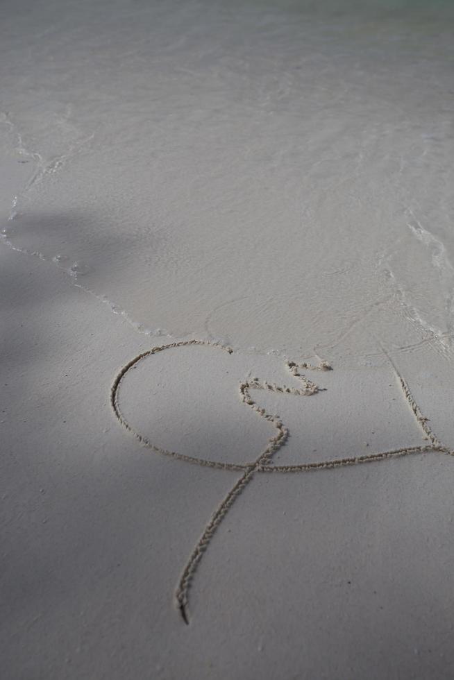 corazones dibujados en la arena de una playa foto