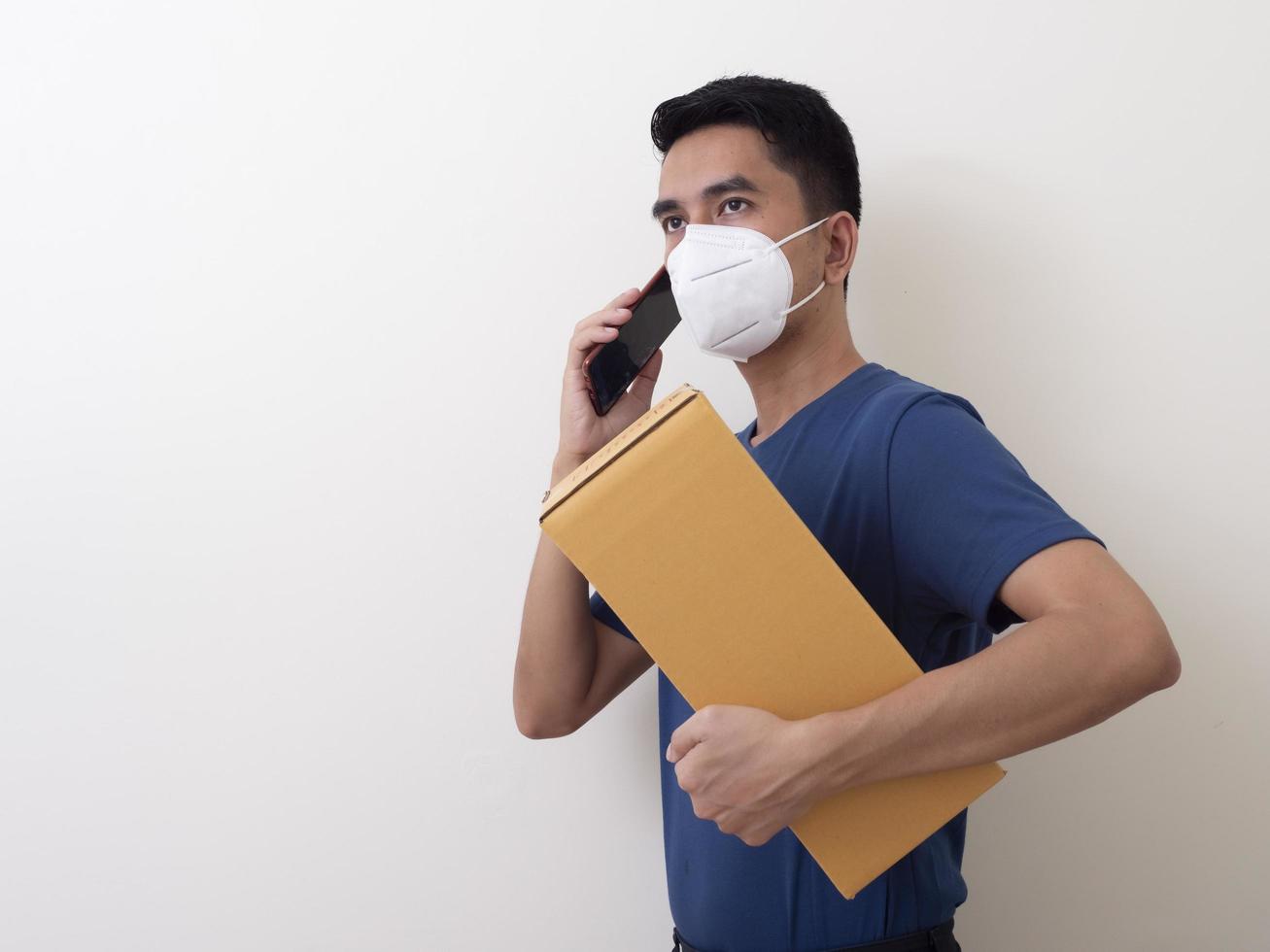 Happy delivery service employee in medical face mask carry cardboard box in hand photo