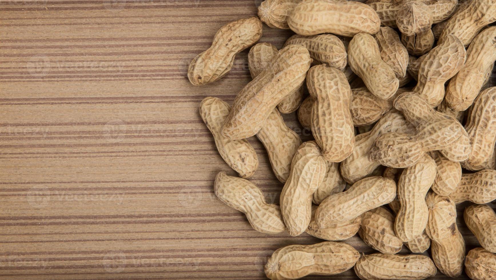 peanuts in shells over wood background photo