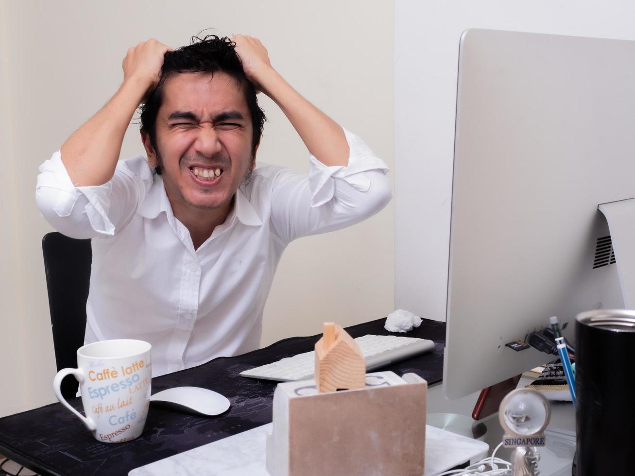 Serious Asian man is working with laptop in his apartment bedroom in concept of Work From Home and Work at Home photo