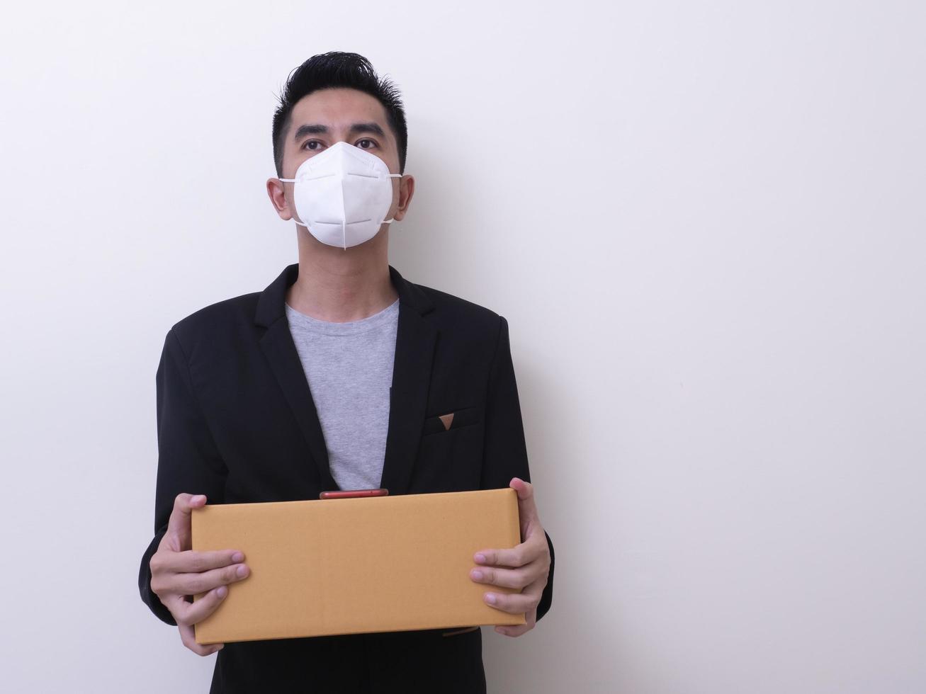 Happy delivery service employee in medical face mask carry cardboard box in hand photo