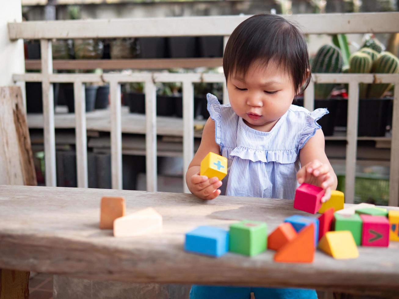 Little asian girl playing with wood blocks on the floor photo