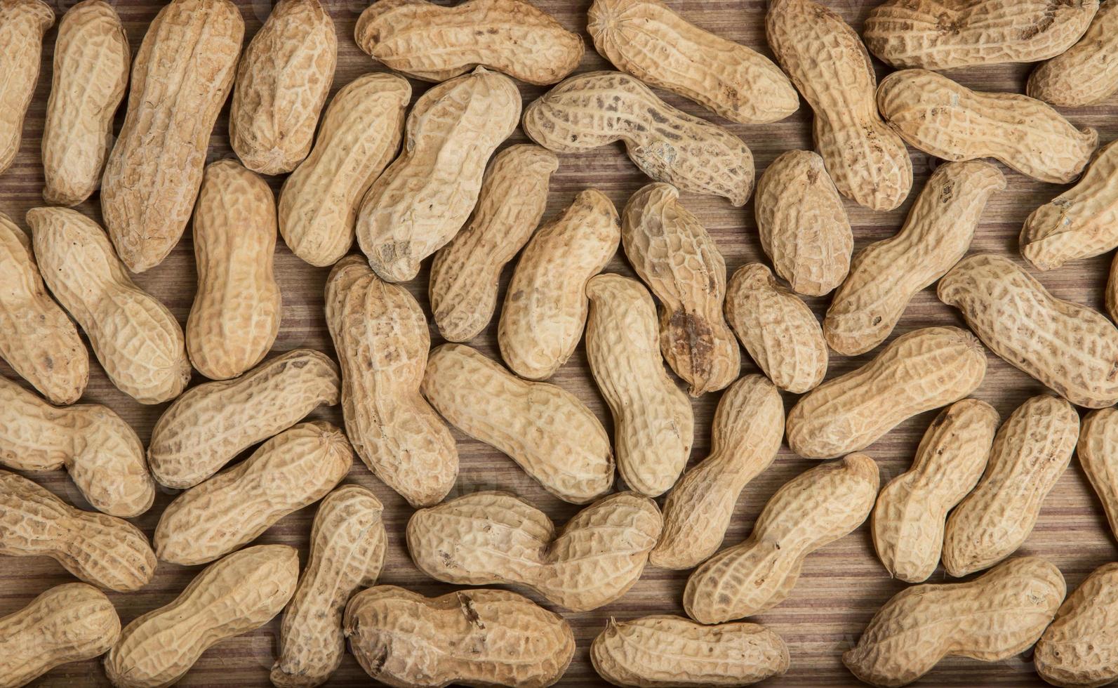 peanuts in shells over wood background photo
