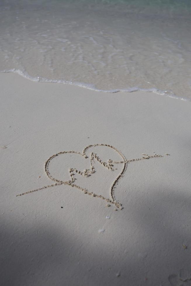 corazones dibujados en la arena de una playa foto