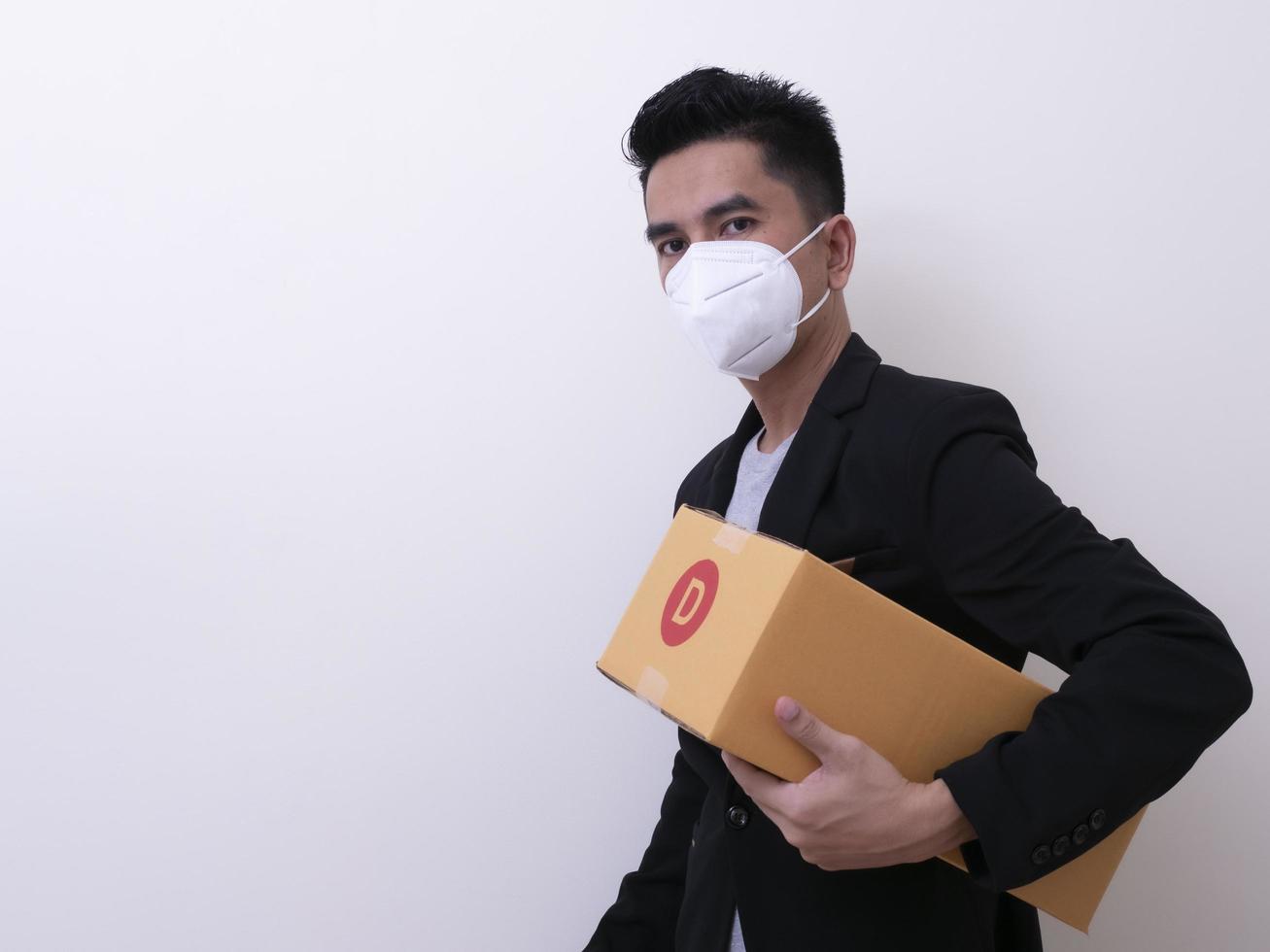 Happy delivery service employee in medical face mask carry cardboard box in hand photo