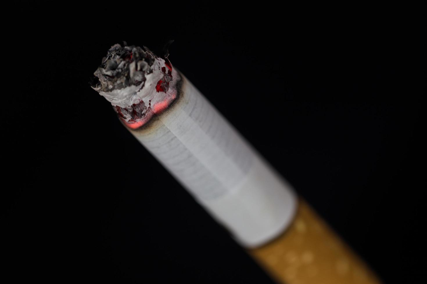 Burning cigarette with smoke on black background photo