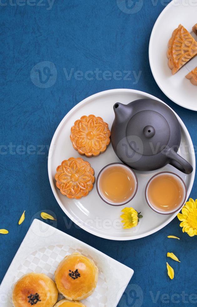 Moon cake for Mid-Autumn Festival, delicious beautiful fresh mooncake on a plate over blue background table, top view, flat lay layout design concept. photo