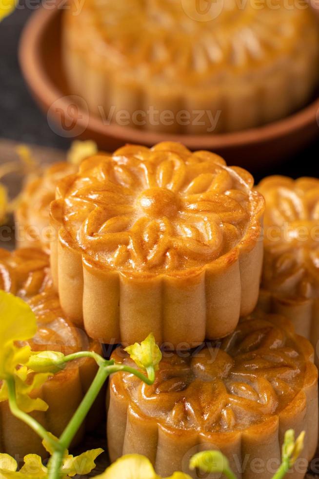 Mooncake, Moon cake for Mid-Autumn Festival, concept of traditional festive food on black slate table with tea and yellow flower, close up, copy space. photo