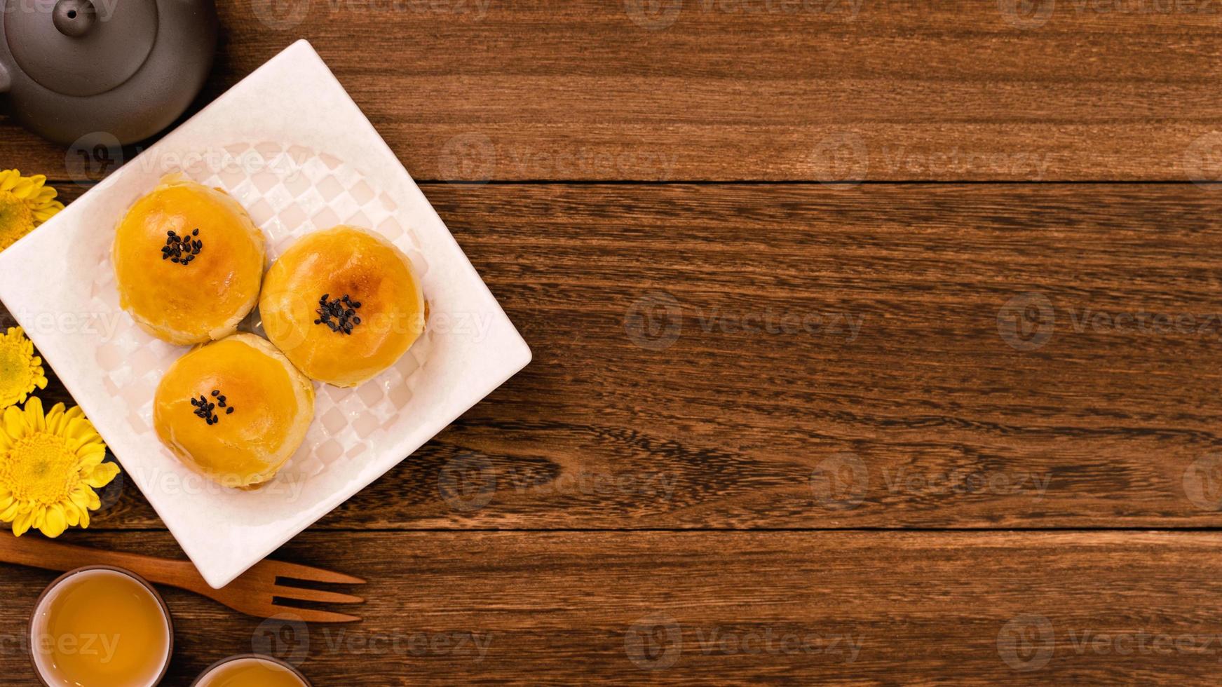 pastel de luna para el festival de mediados de otoño, delicioso y hermoso pastel de luna fresco en un plato sobre una mesa de fondo de madera oscura, vista superior, concepto de diseño plano. foto