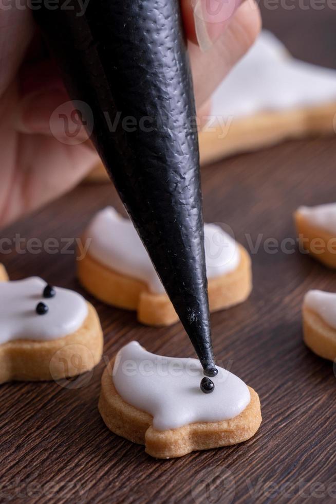 Close up of decorating cute Halloween ghost cookies with frosting. photo