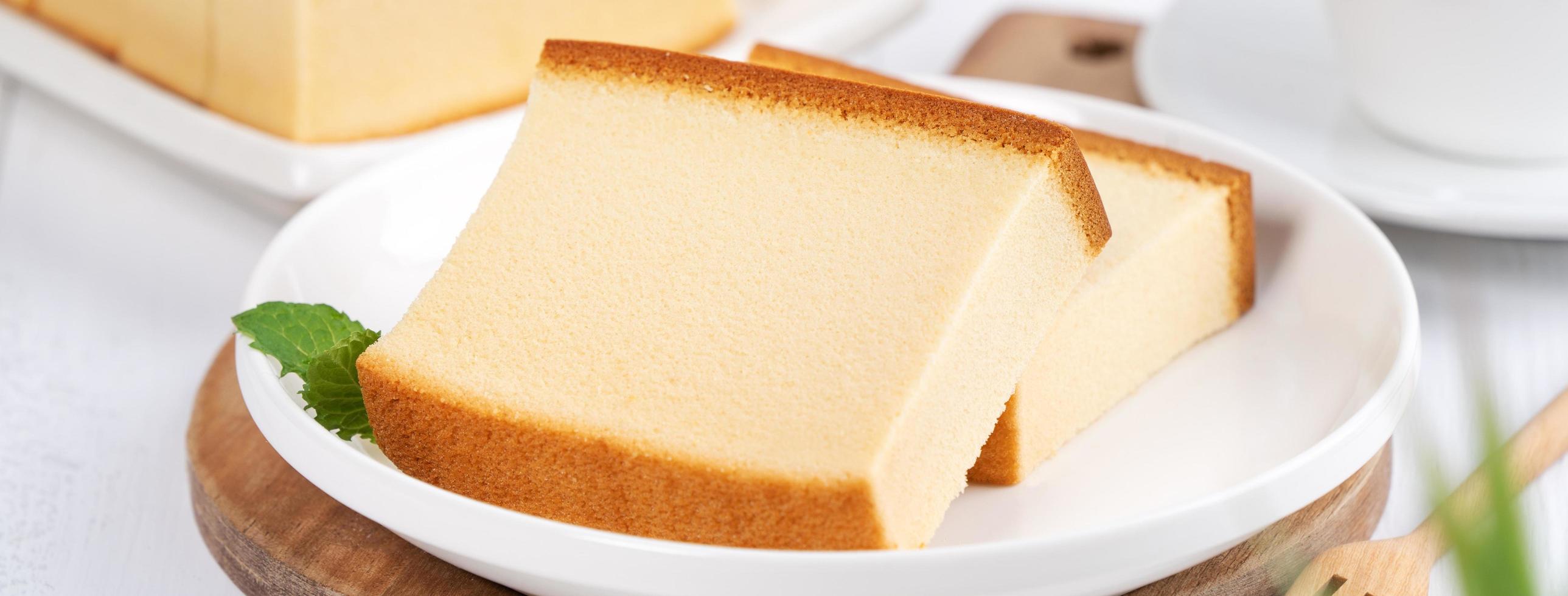 castella kasutera - hermosa y deliciosa comida japonesa de bizcocho en rodajas en un plato blanco sobre una mesa rústica de madera blanca, primer plano, concepto de diseño de espacio de copia. foto