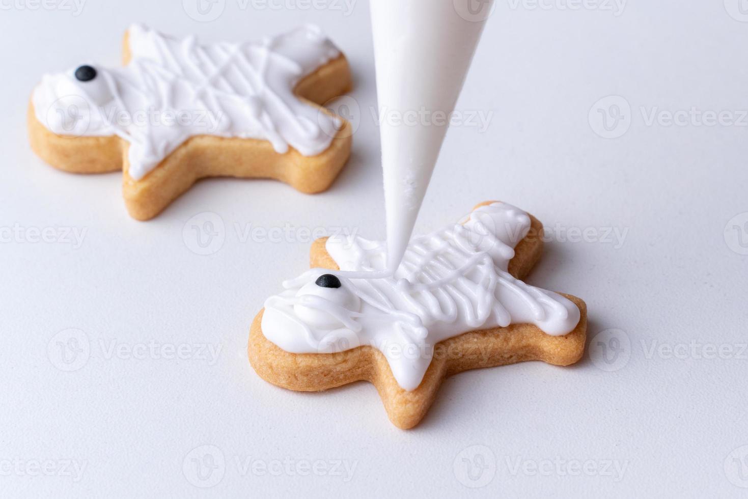 Close up of decorating cute Halloween cookies with frosting in icing bag. photo