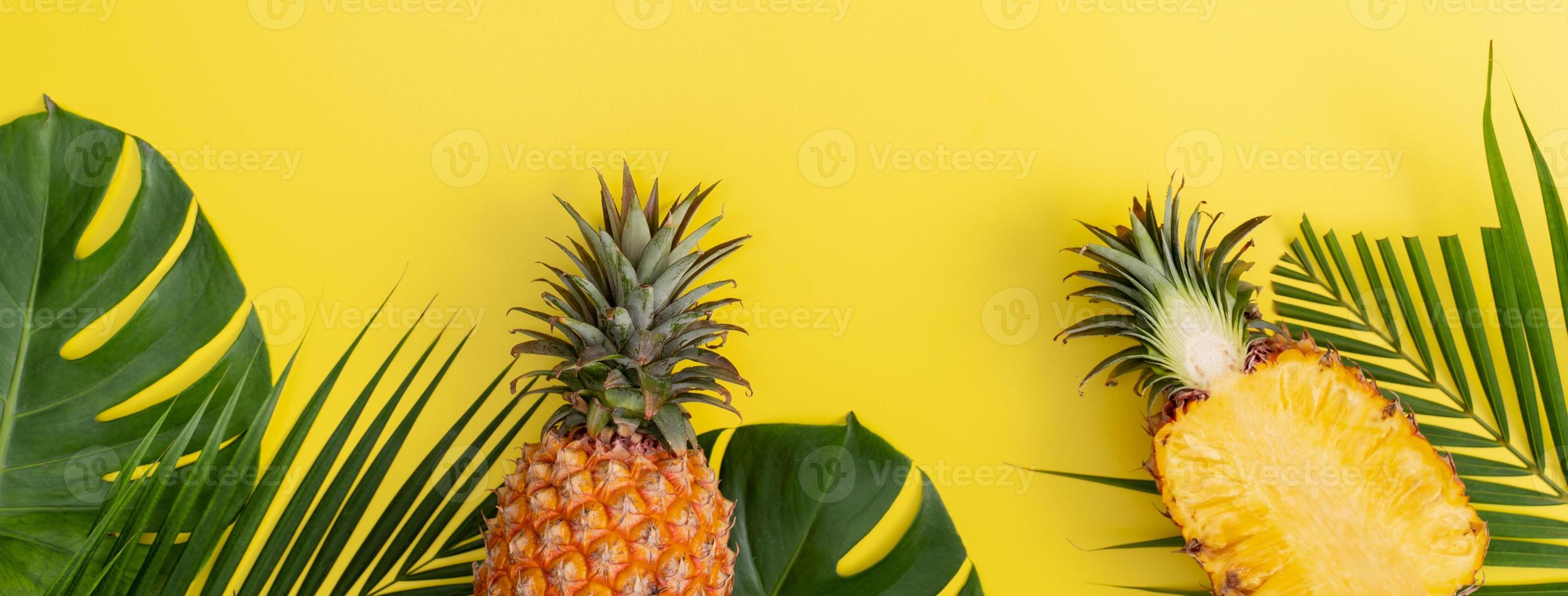 Beautiful pineapple on tropical palm monstera leaves isolated on bright pastel yellow background, top view, flat lay, overhead above summer fruit. photo