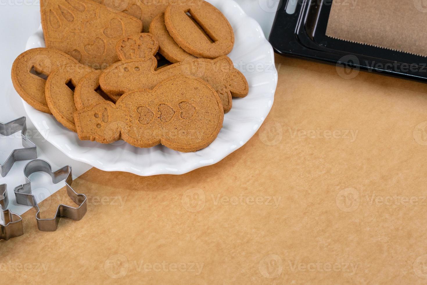 Young woman is decorating Christmas Gingerbread House cookies biscuit at home with frosting topping in icing bag, close up, lifestyle. photo