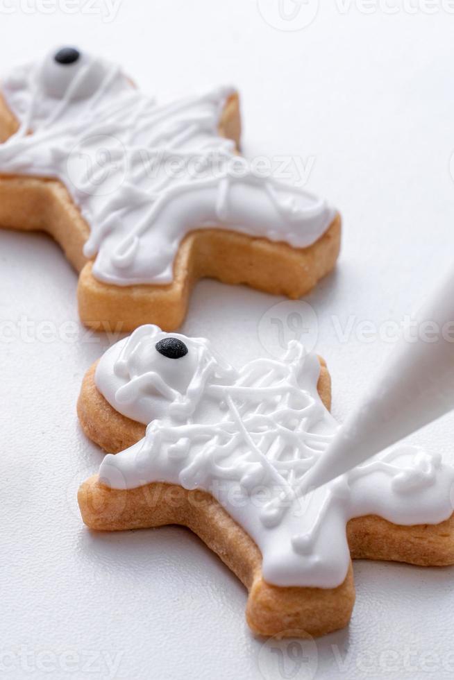 Close up of decorating cute Halloween cookies with frosting in icing bag. photo