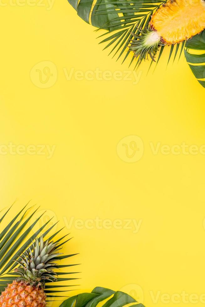 Beautiful pineapple on tropical palm monstera leaves isolated on bright pastel yellow background, top view, flat lay, overhead above summer fruit. photo