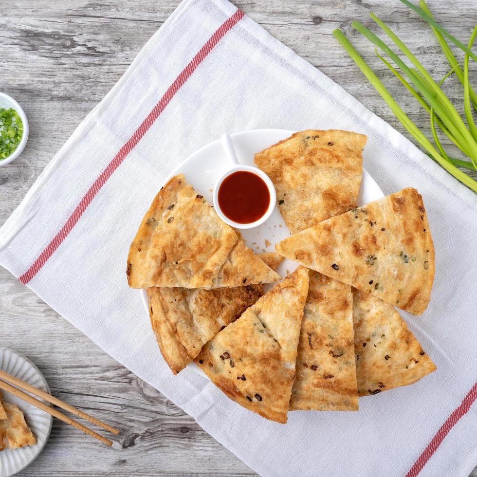 Taiwanese food - delicious flaky scallion pie pancakes on bright wooden table background, traditional snack in Taiwan, top view. photo