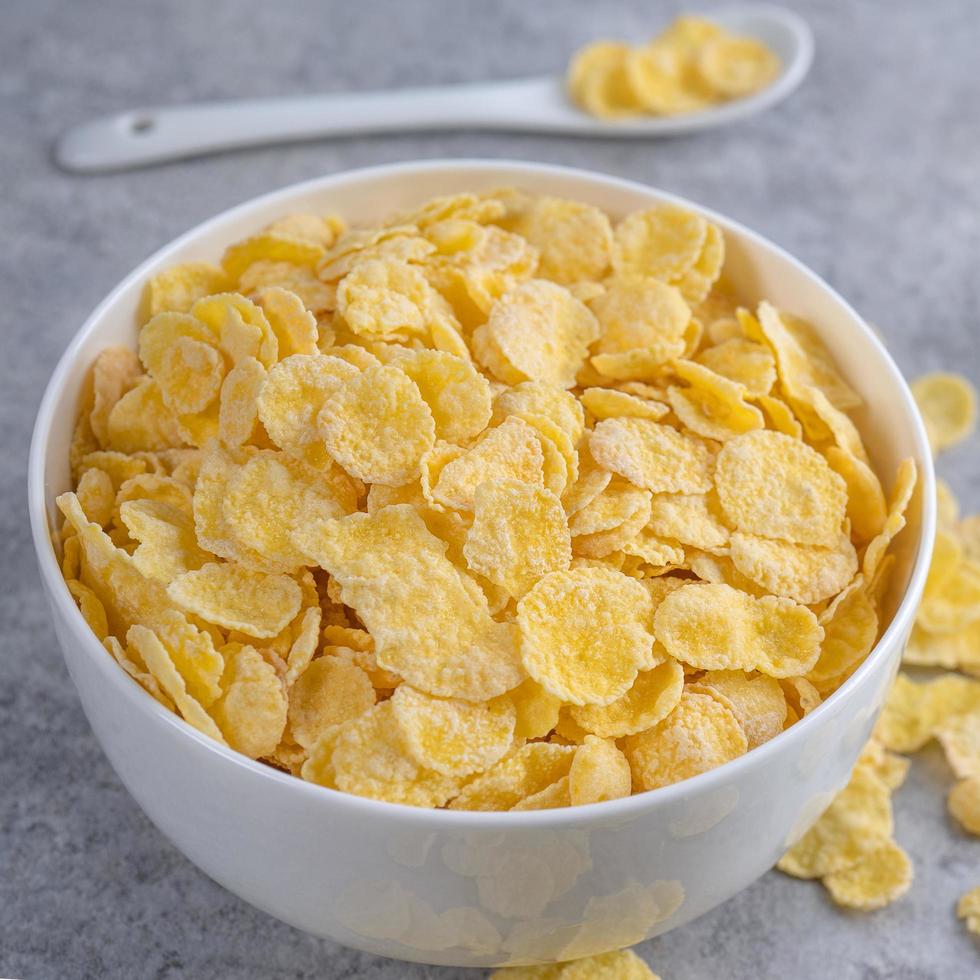 Corn flakes bowl sweeties with milk on gray cement background, close up, fresh and healthy breakfast design concept. photo