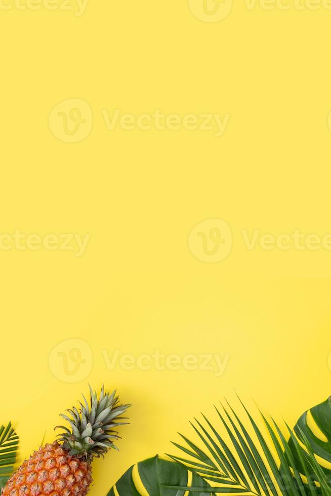 Beautiful pineapple on tropical palm monstera leaves isolated on bright pastel yellow background, top view, flat lay, overhead above summer fruit. photo