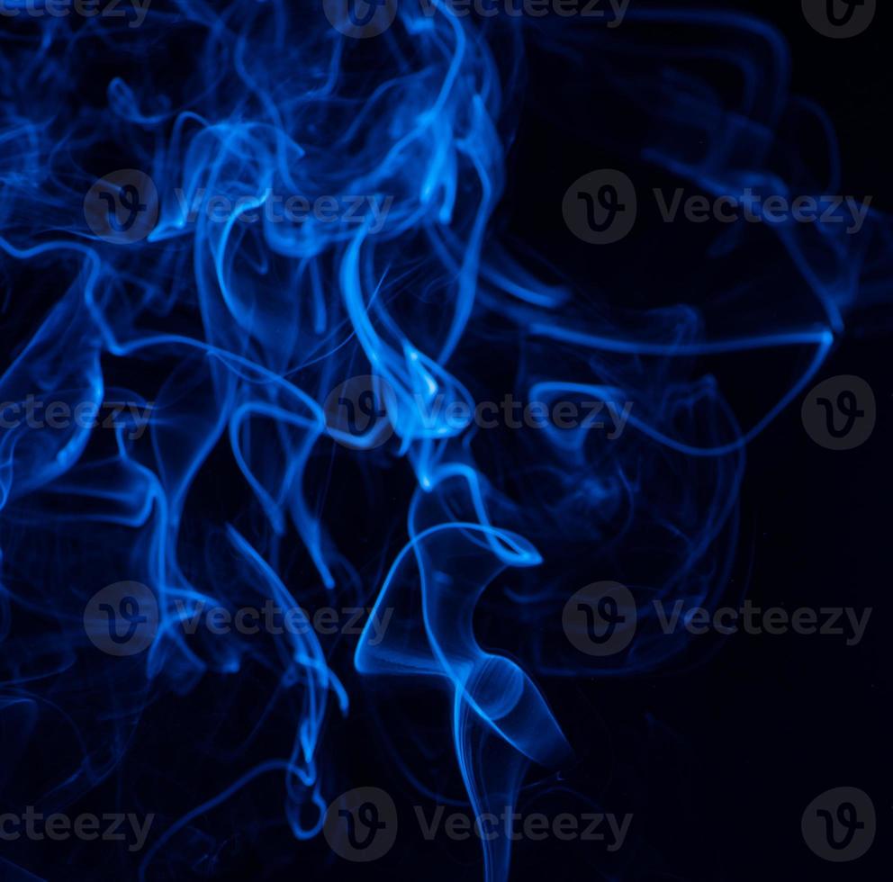 Conceptual image of blue color smoke isolated on dark black background, Halloween concept design element. photo