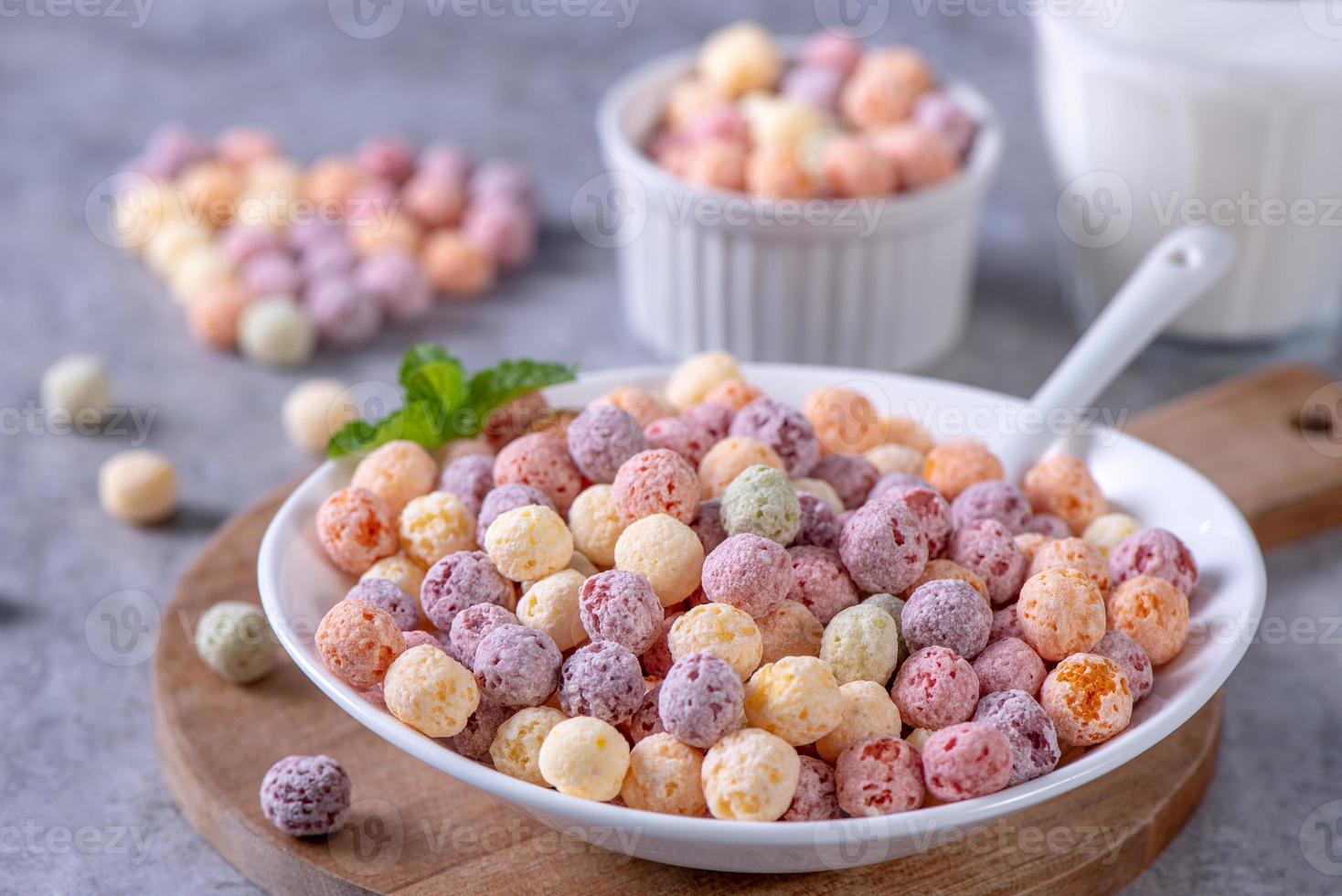 Colorful cereal corn balls mix, fruit flavor bowl sweets on gray cement background, close up, fresh, delicious and healthy breakfast, copy space design concept. photo