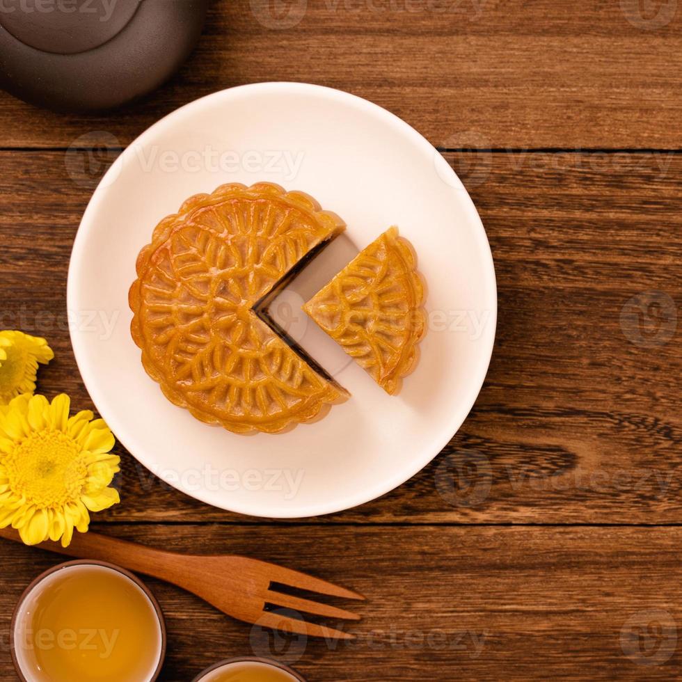 pastel de luna para el festival de mediados de otoño, delicioso y hermoso pastel de luna fresco en un plato sobre una mesa de fondo de madera oscura, vista superior, concepto de diseño plano. foto