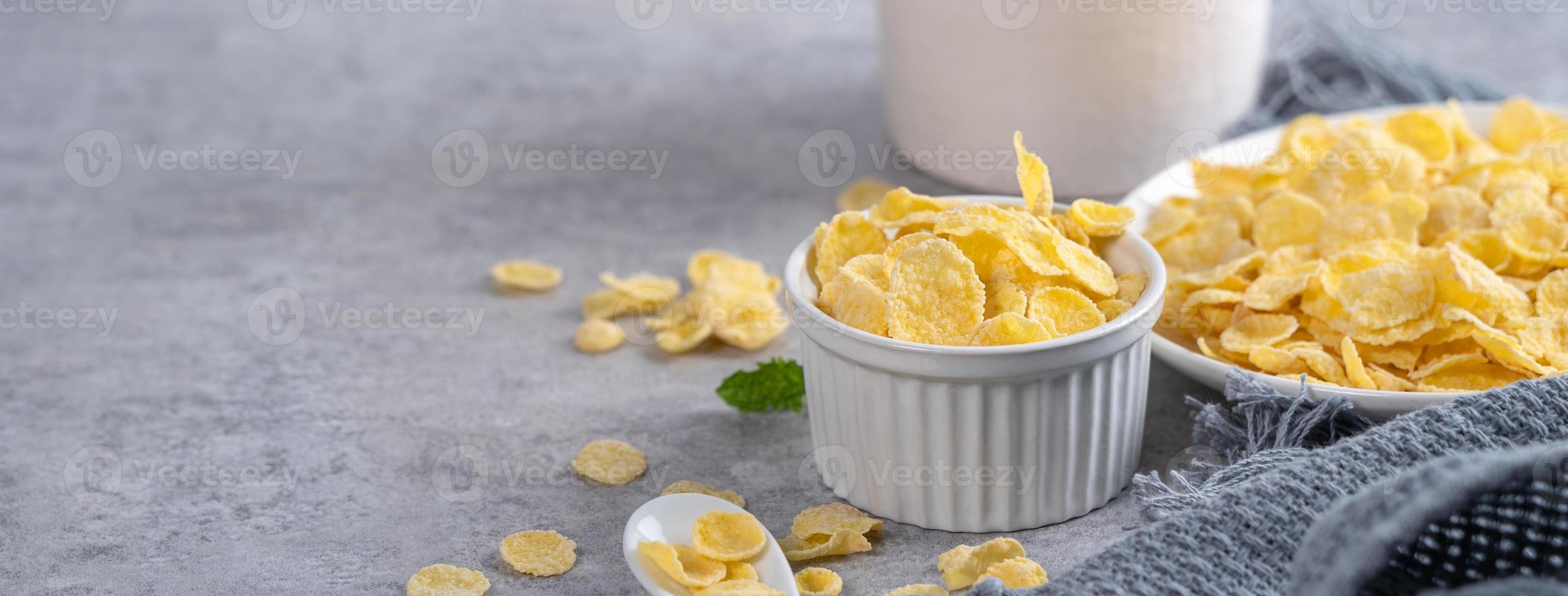 Corn flakes bowl sweeties with milk on gray cement background, close up, fresh and healthy breakfast design concept. photo