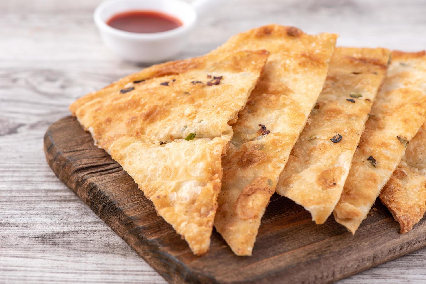 Taiwanese food - delicious flaky scallion pie pancakes on bright wooden table background, traditional snack in Taiwan, close up. photo