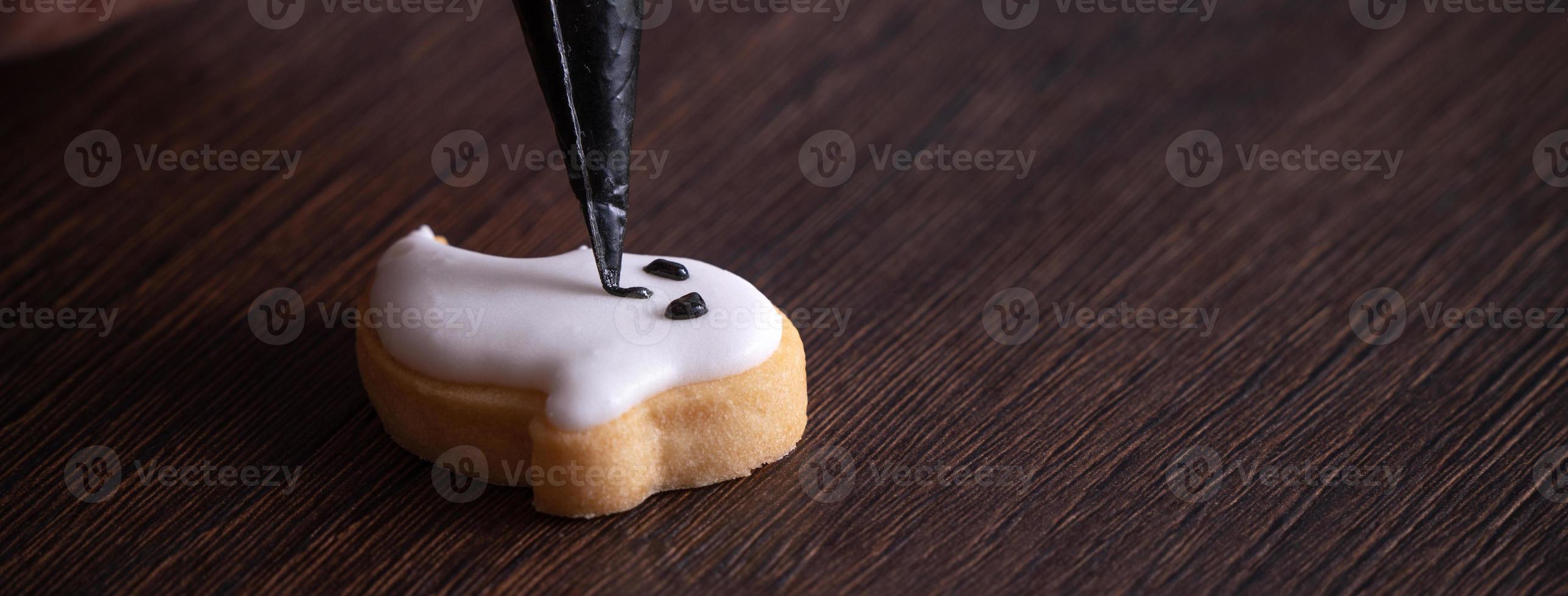 Close up of decorating cute Halloween ghost cookies with frosting. photo