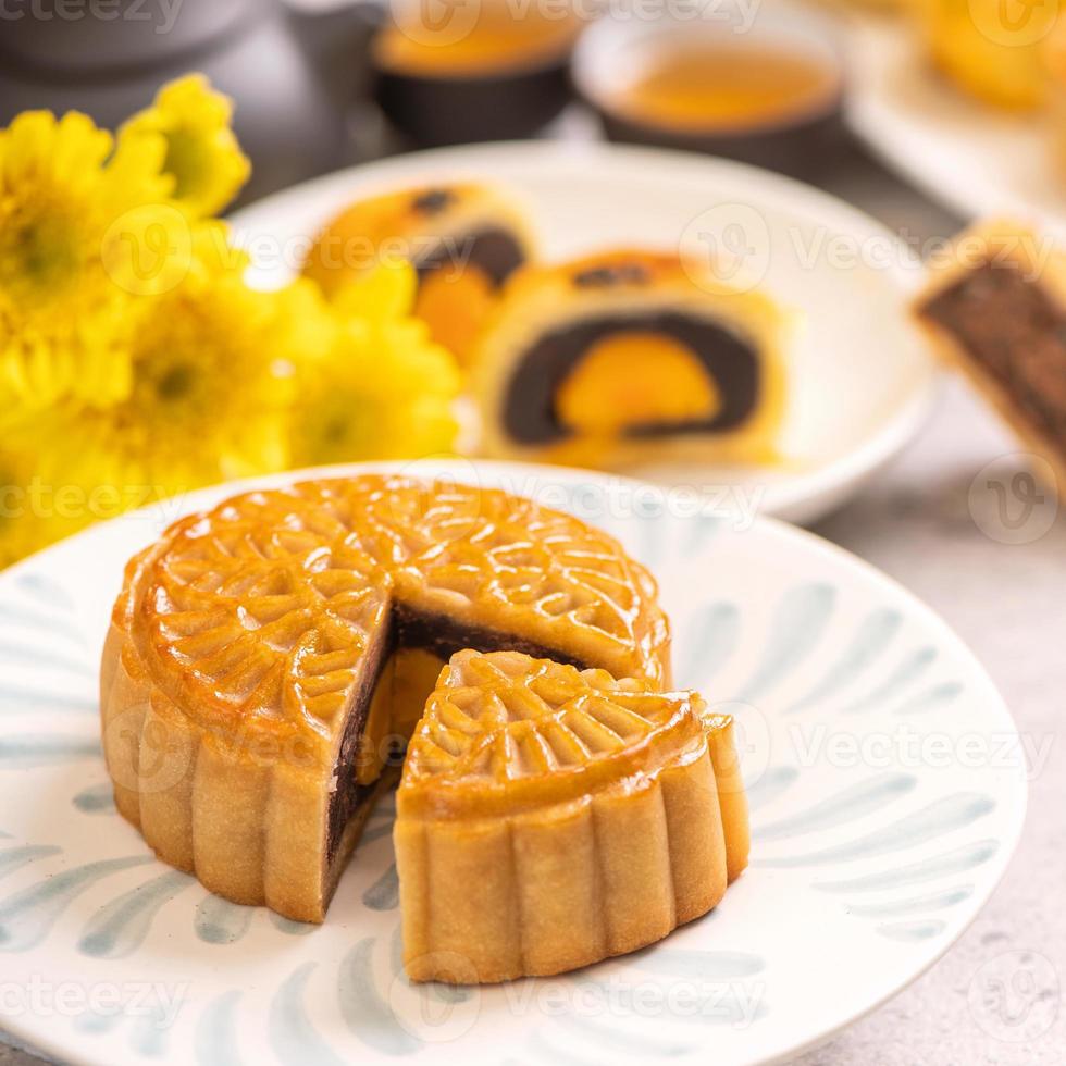 Tasty baked egg yolk pastry moon cake for Mid-Autumn Festival on bright wooden table background. Chinese festive food concept, close up, copy space. photo