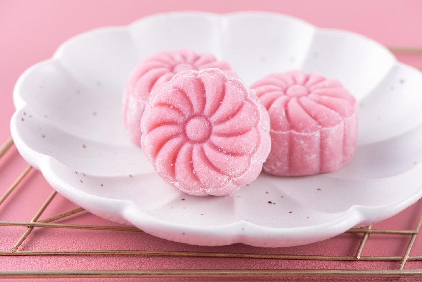 Colorful snow skin moon cake, sweet snowy mooncake, traditional savory dessert for Mid-Autumn Festival on pastel pale pink background, close up, lifestyle. photo