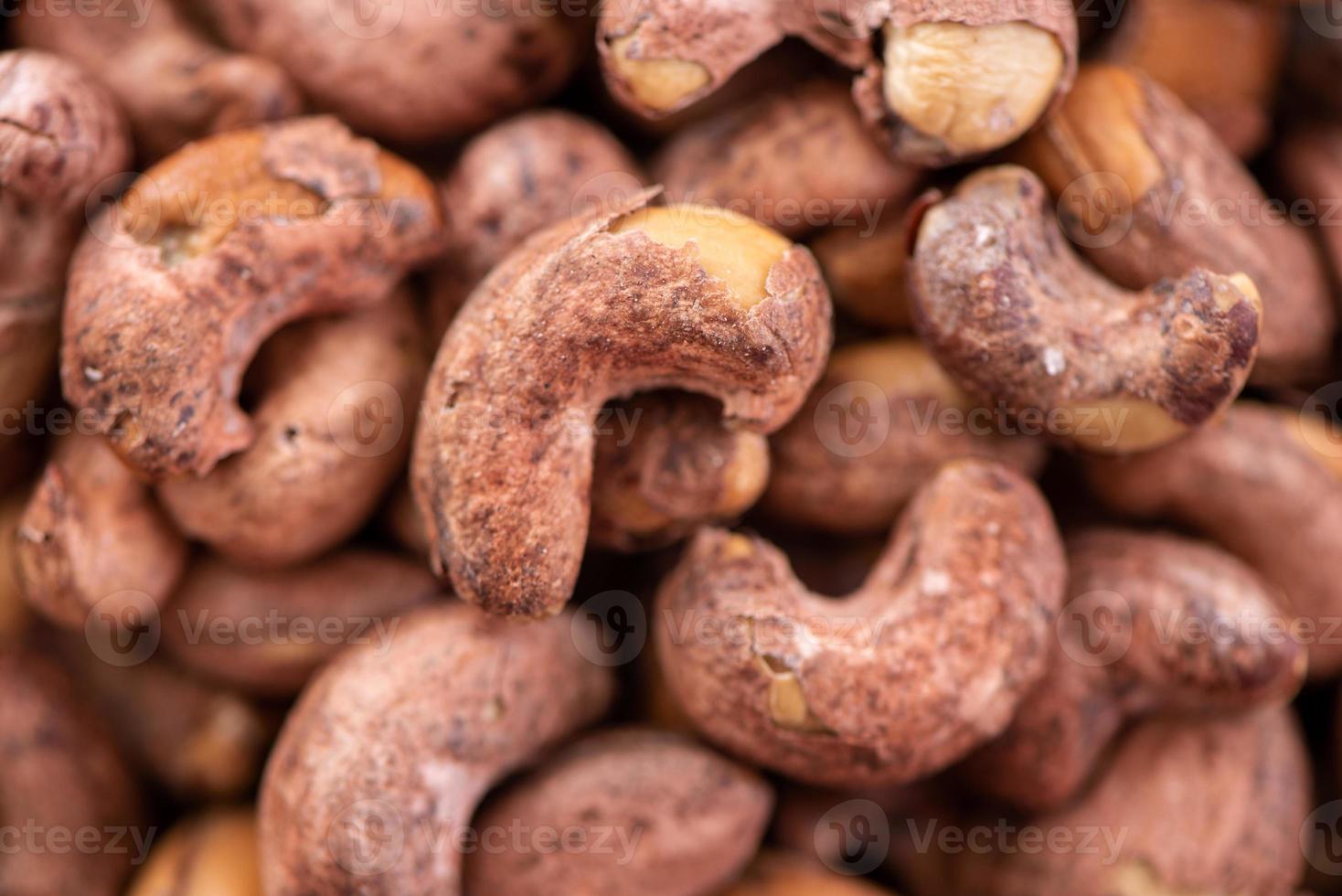 Cashew nuts with peel in a plate on wooden tray and table background, healthy raw food plate. photo
