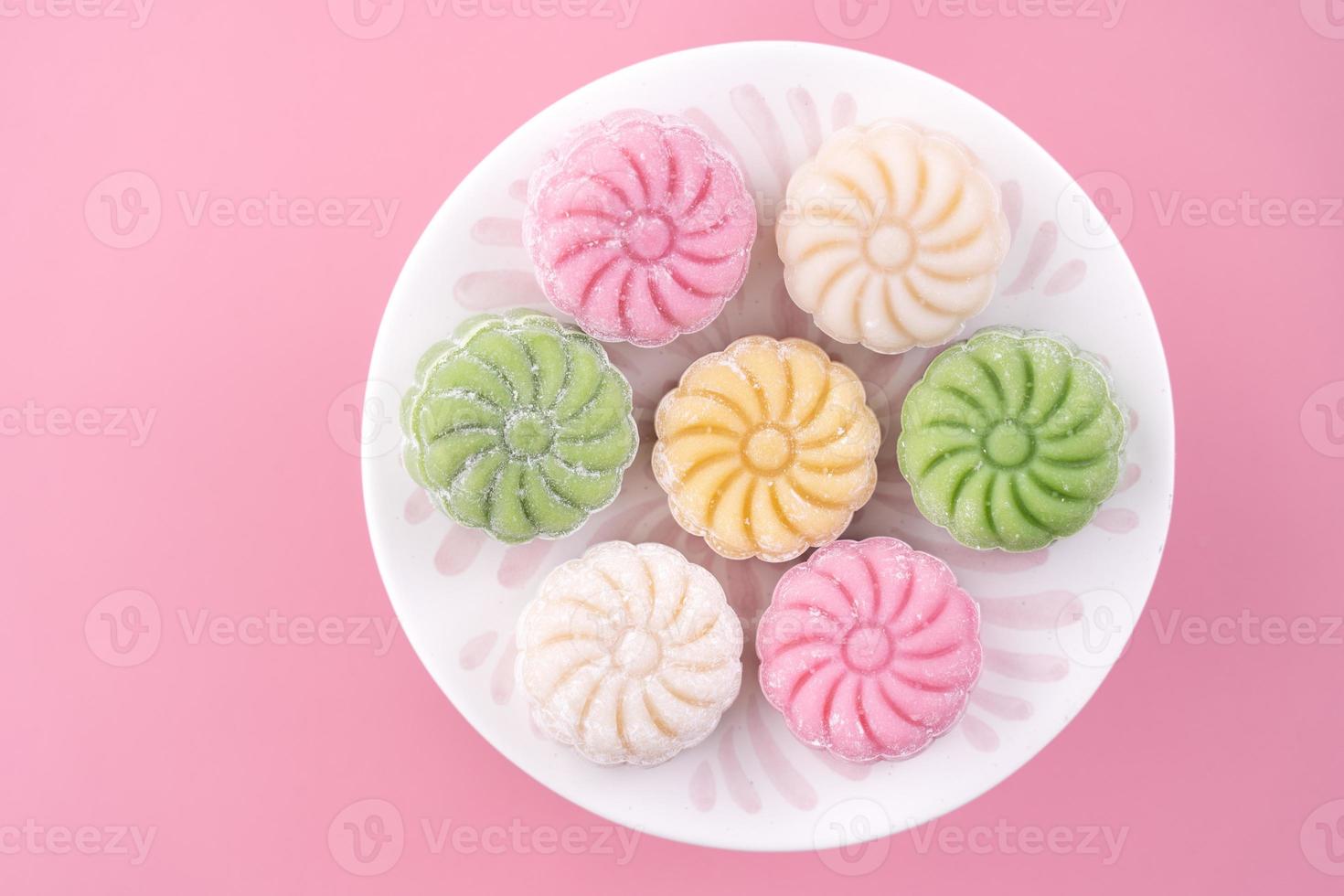 Colorful snow skin moon cake, sweet snowy mooncake, traditional savory dessert for Mid-Autumn Festival on pastel pale pink background, close up, lifestyle. photo