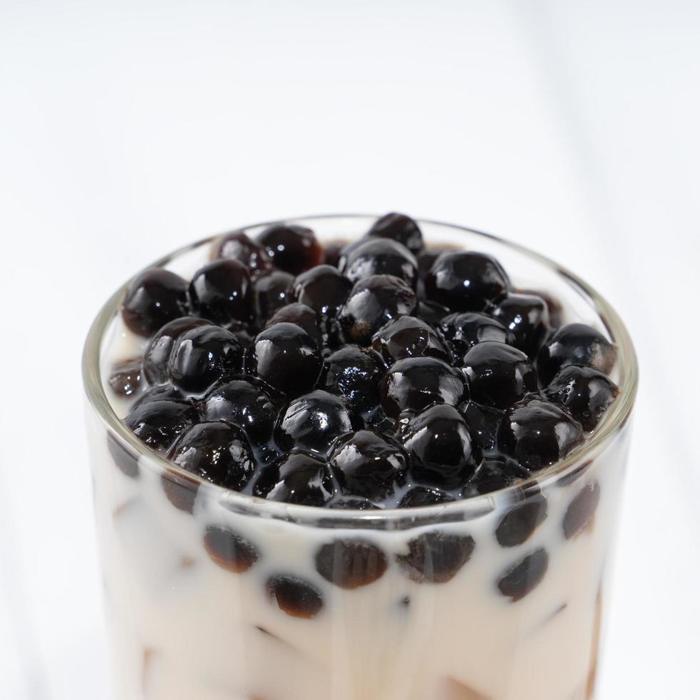 Bubble milk tea with tapioca pearl topping, famous Taiwanese drink on white wooden table background in drinking glass, close up, copy space photo