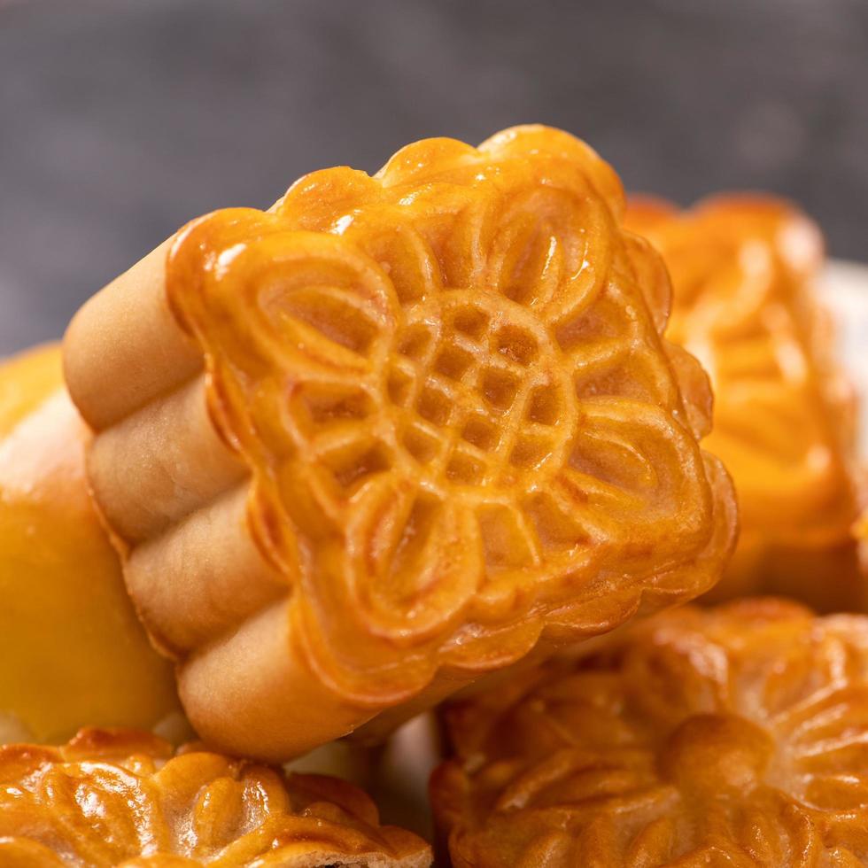 Tasty baked egg yolk pastry moon cake for Mid-Autumn Festival on black slate dark background. Chinese festive food concept, close up, copy space. photo