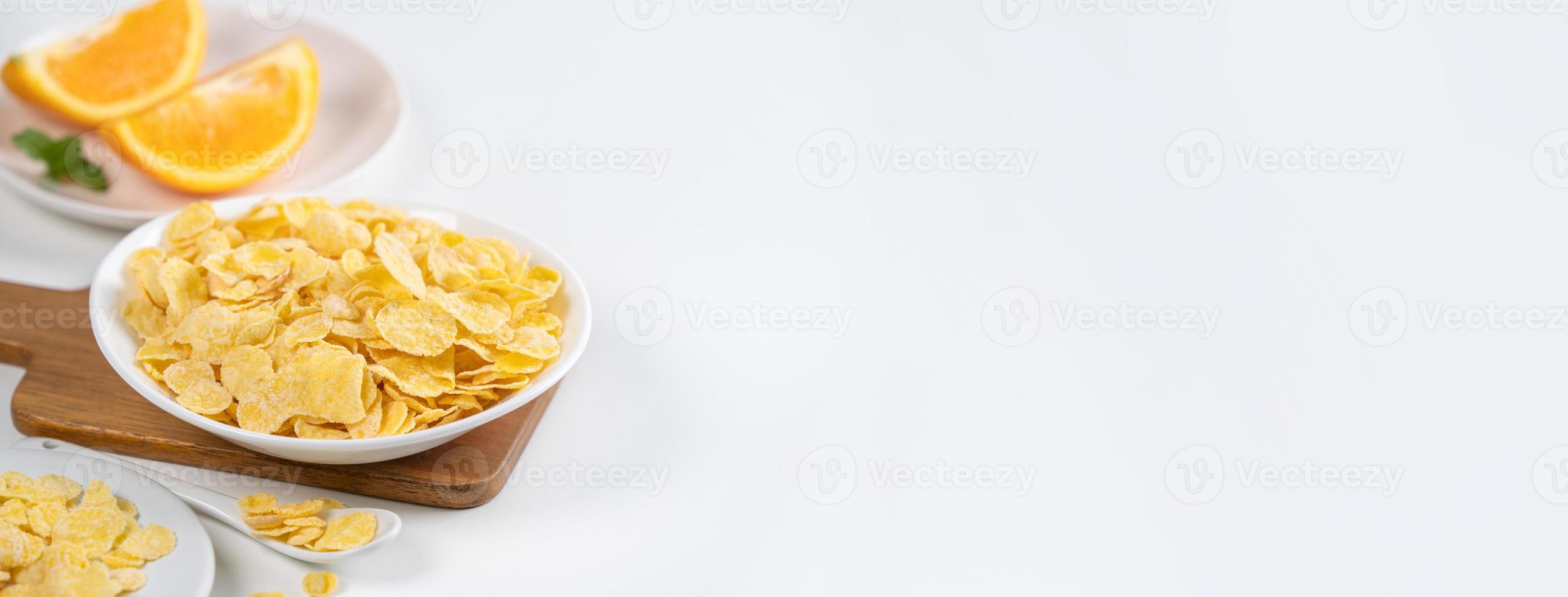 Corn flakes bowl sweeties with milk and orange on white background, close up, fresh and healthy breakfast design concept. photo