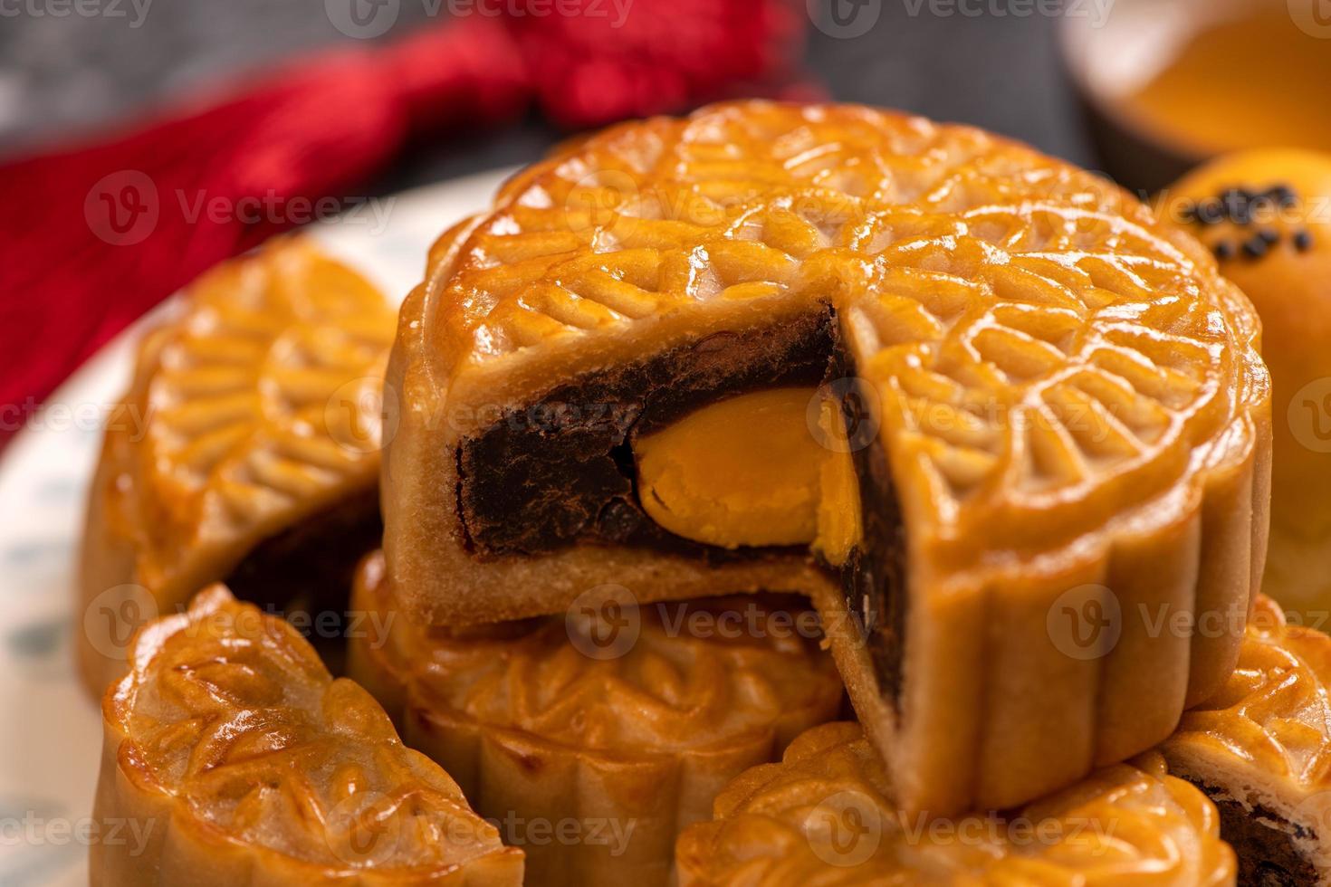 Tasty baked egg yolk pastry moon cake for Mid-Autumn Festival on black slate dark background. Chinese festive food concept, close up, copy space. photo