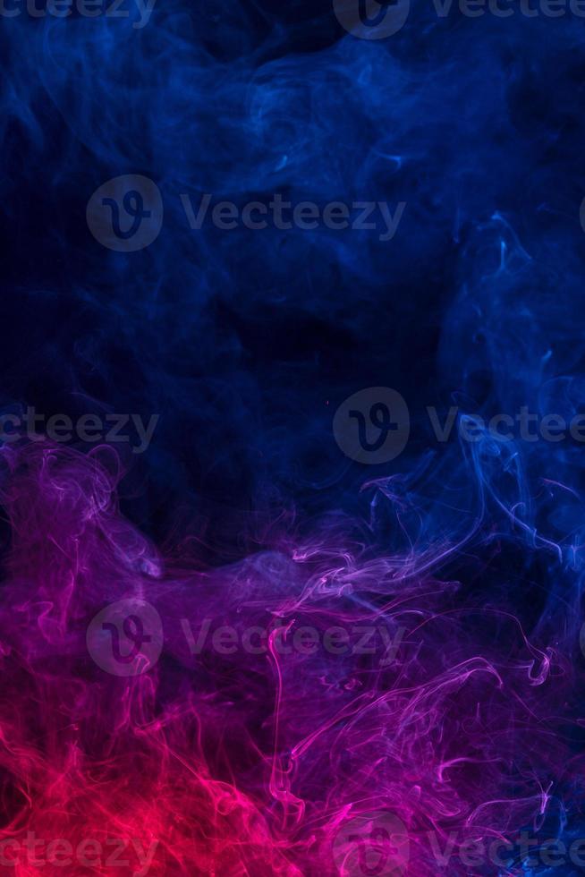 Conceptual image of multi-colored smoke isolated on dark black background, Halloween design element. photo