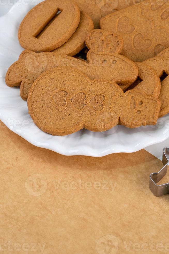 Young woman is decorating Christmas Gingerbread House cookies biscuit at home with frosting topping in icing bag, close up, lifestyle. photo