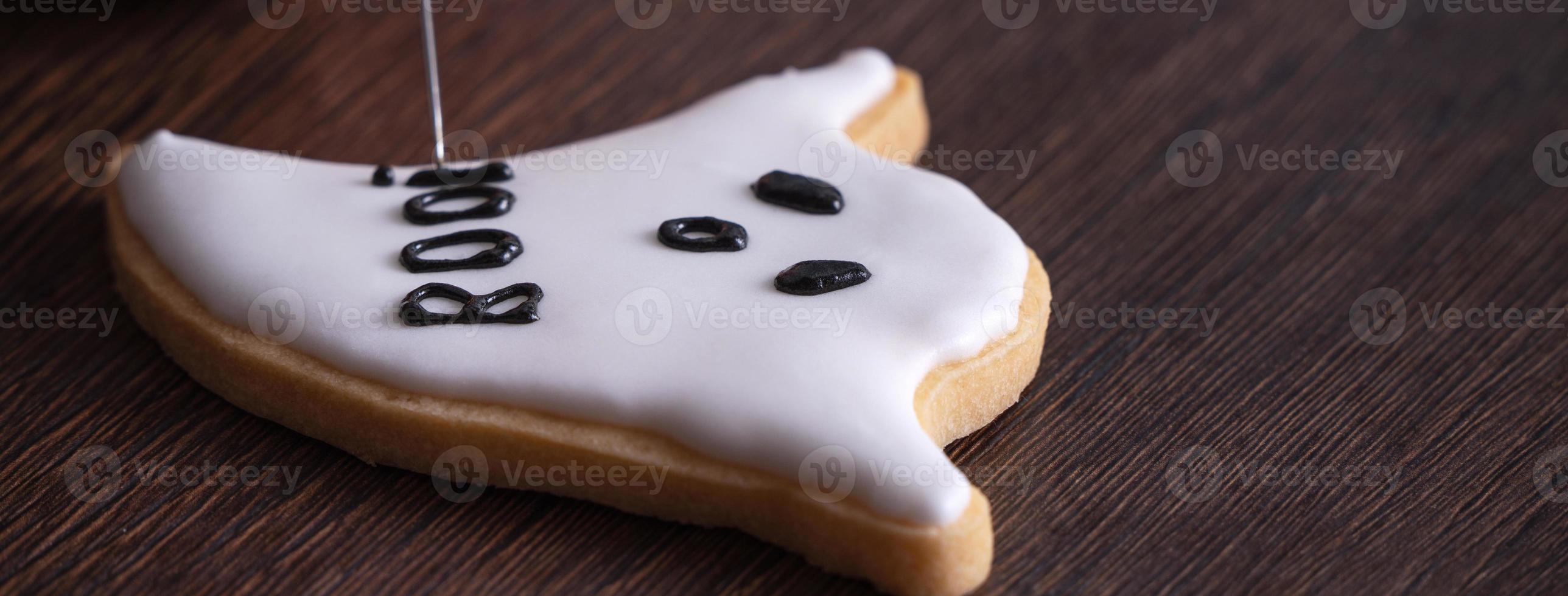 Close up of decorating cute Halloween ghost cookies with frosting. photo