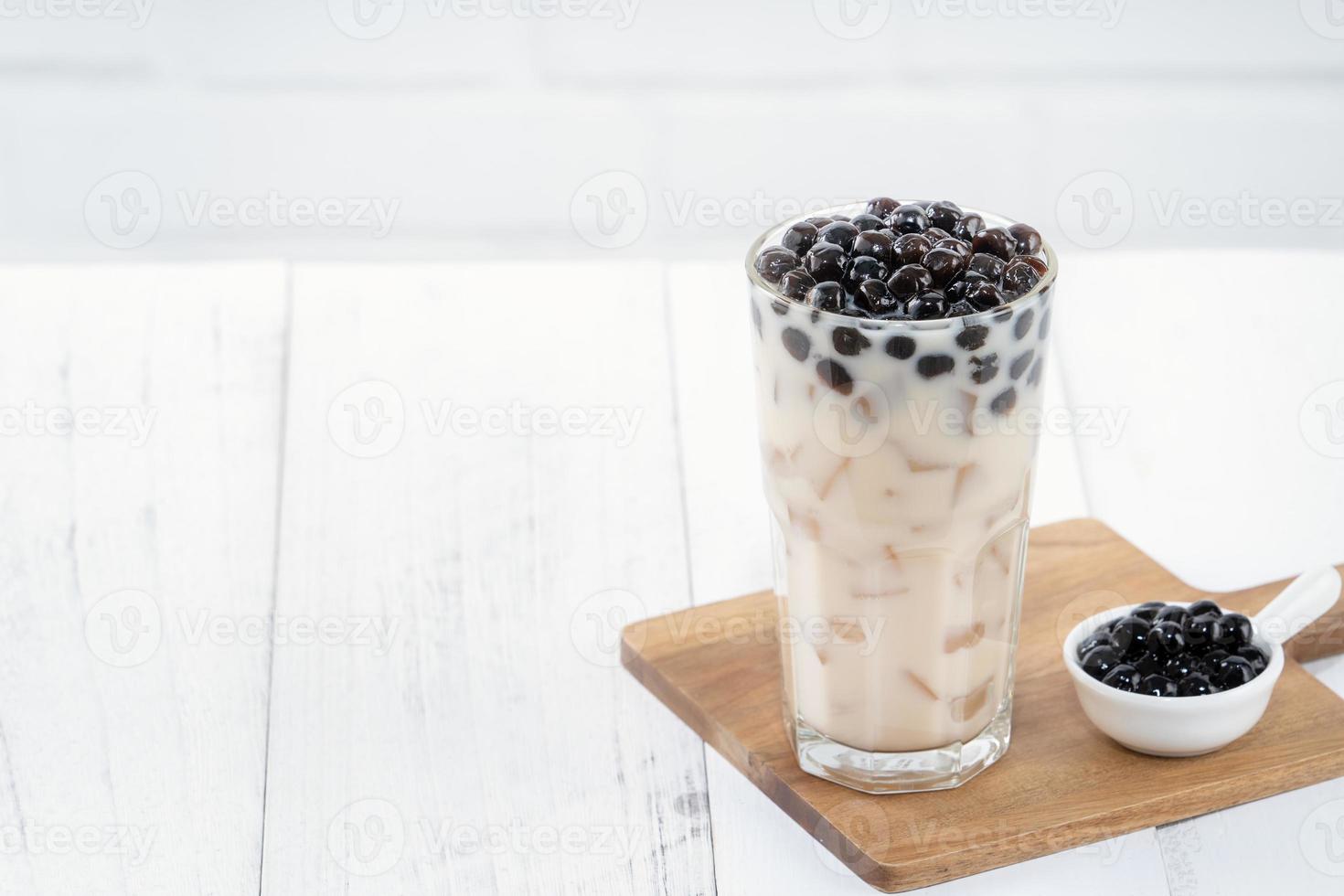 Bubble milk tea with tapioca pearl topping, famous Taiwanese drink on white wooden table background in drinking glass, close up, copy space photo