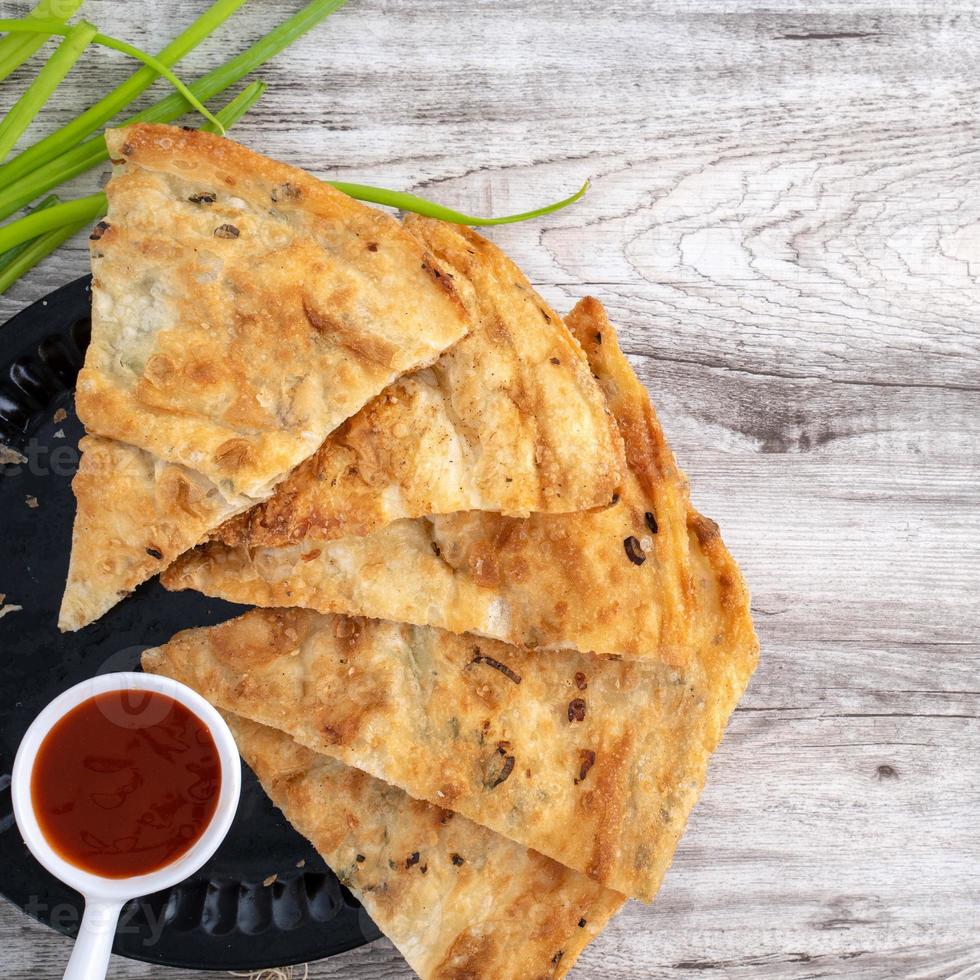 Taiwanese food - delicious flaky scallion pie pancakes on bright wooden table background, traditional snack in Taiwan, top view. photo