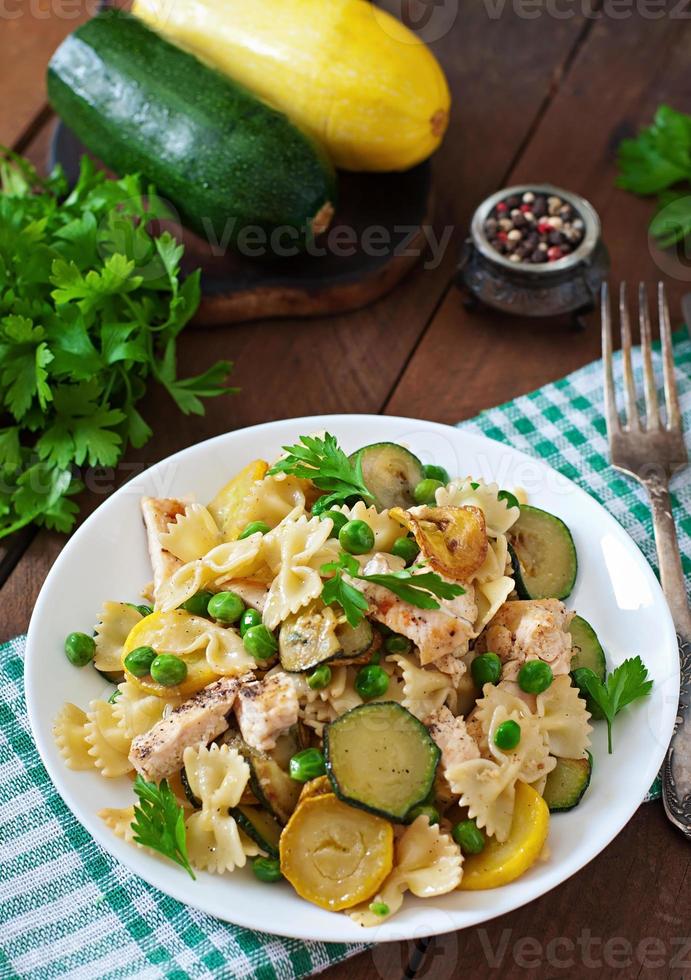 Pasta with zucchini, chicken and green peas photo