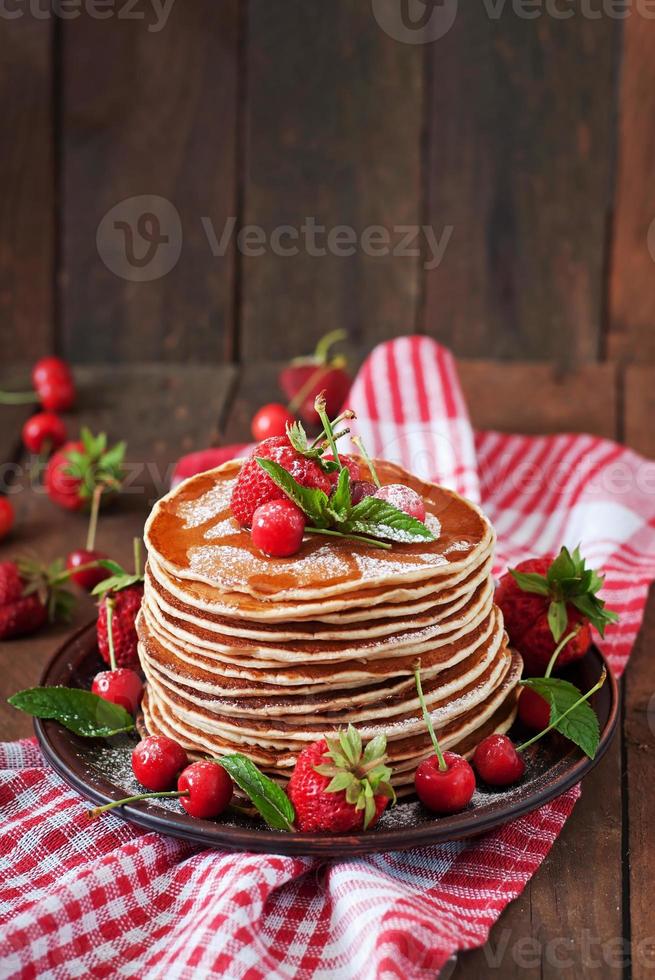 tortitas con frutos rojos y almíbar en estilo rústico foto