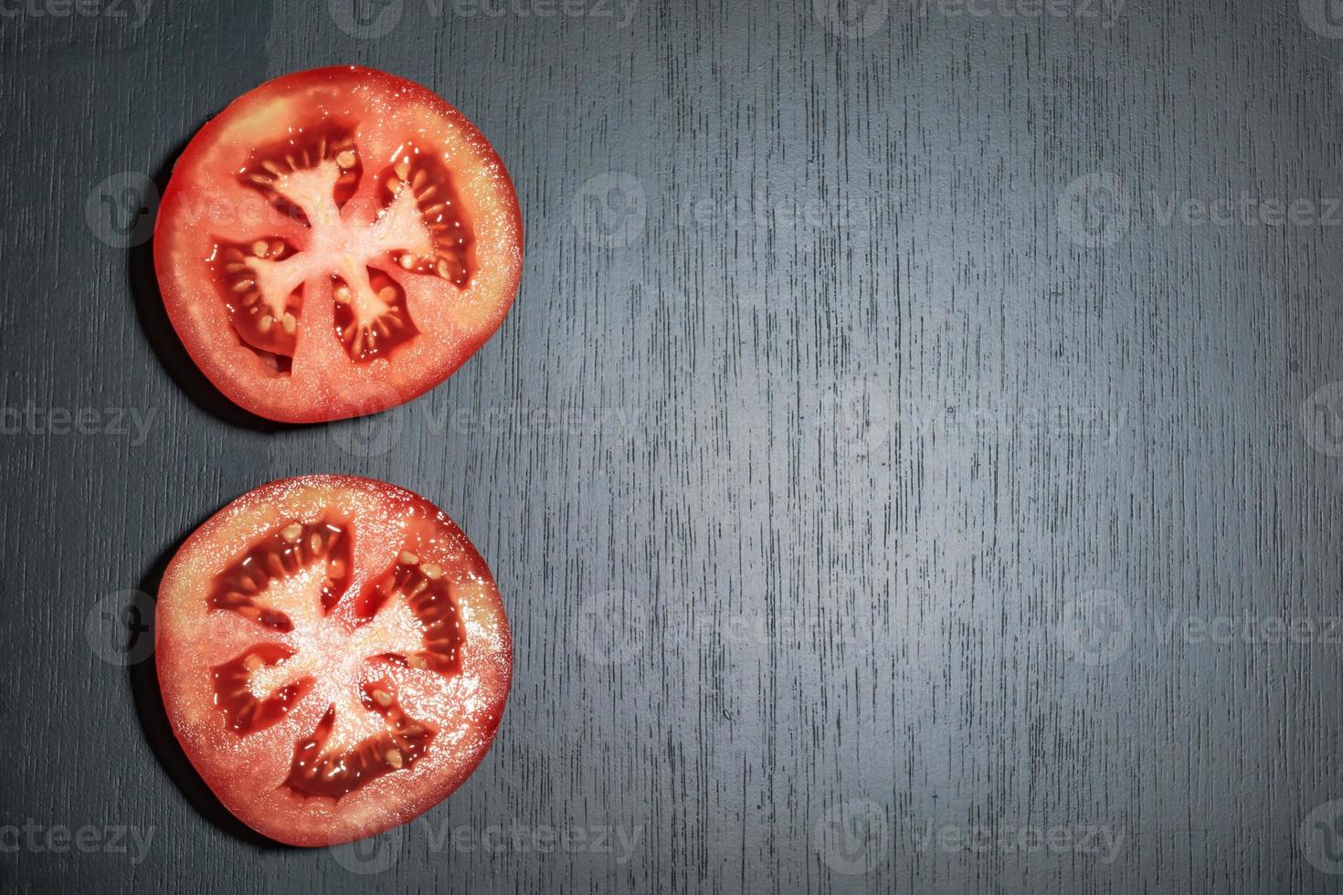 rebanada de tomate de alimentos saludables en el espacio de copia de la mesa de madera negra. foto