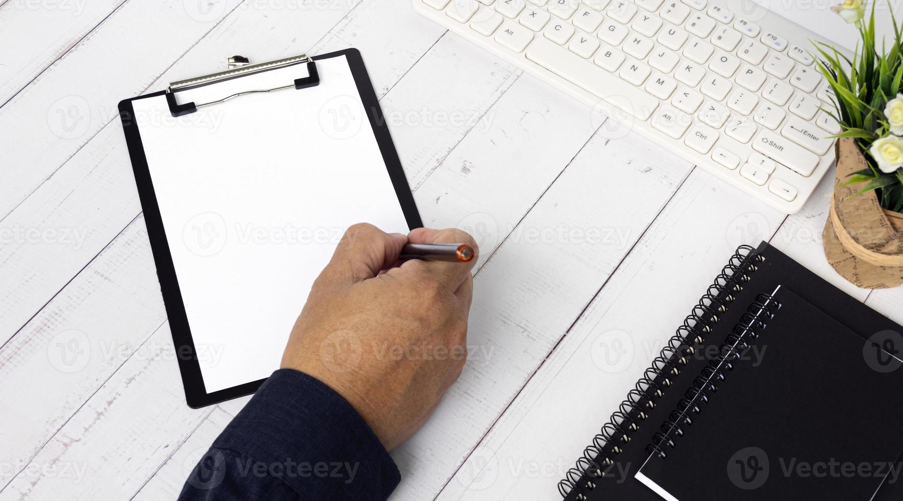 Businessman hands with pen writing notebook on office desk table with. photo